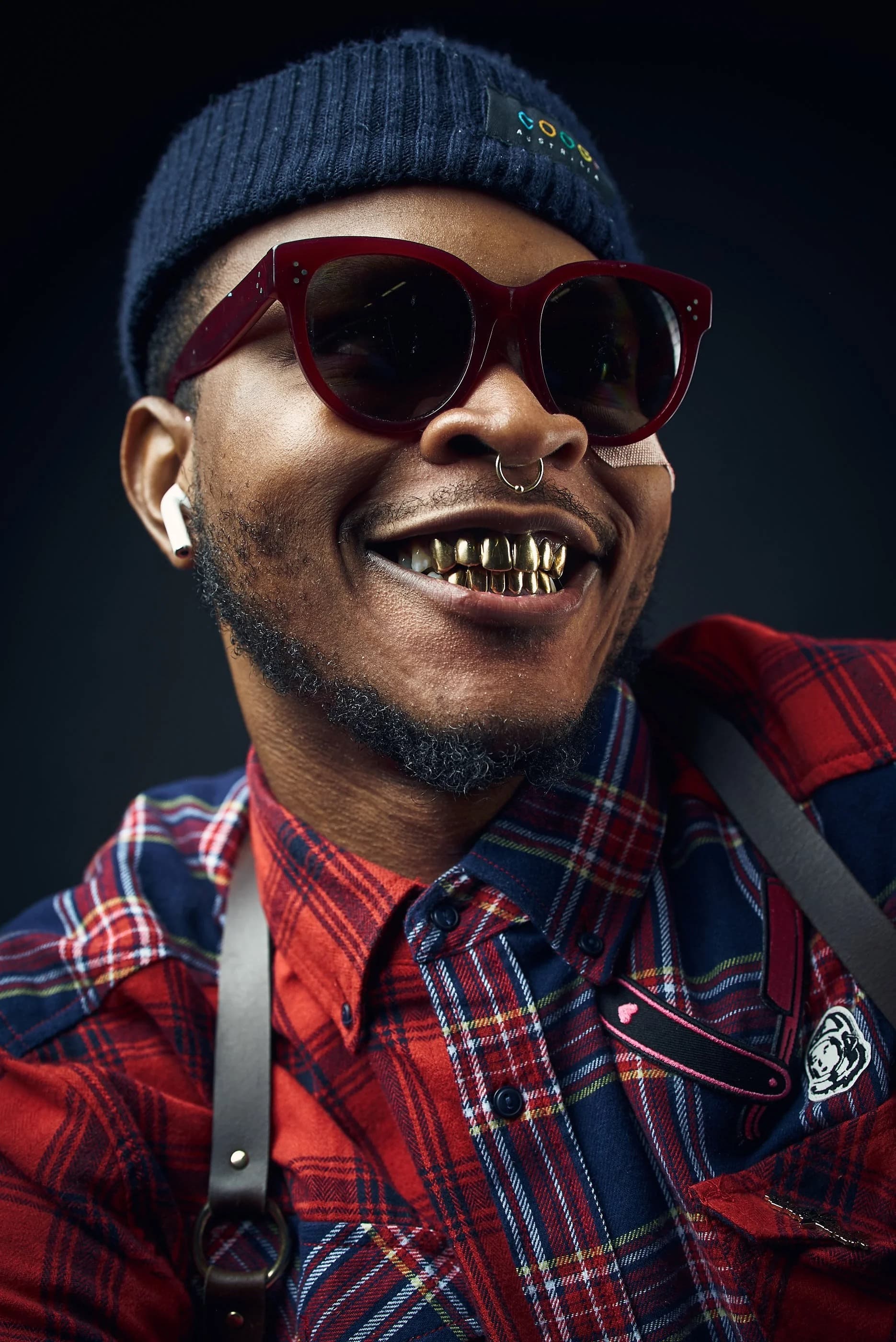 Atlanta artist Paper Frank smiling in a knit cap and red sunglasses